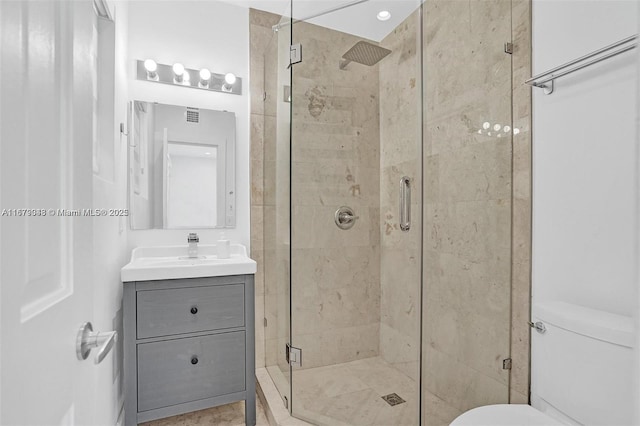 bathroom featuring vanity, toilet, and a shower with shower door