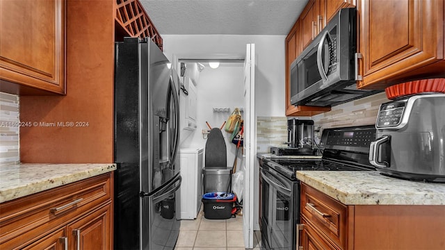 kitchen with black appliances, a textured ceiling, tasteful backsplash, light tile patterned flooring, and light stone countertops