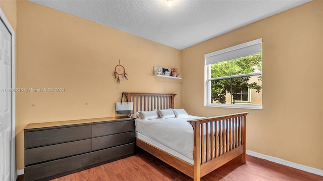 bedroom with a textured ceiling and hardwood / wood-style flooring