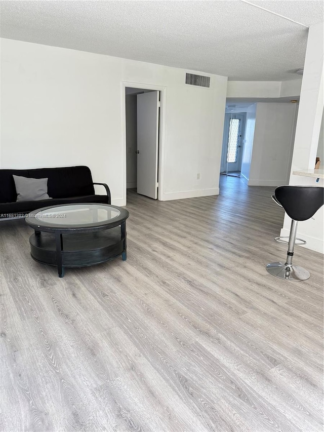 living room featuring light hardwood / wood-style floors and a textured ceiling