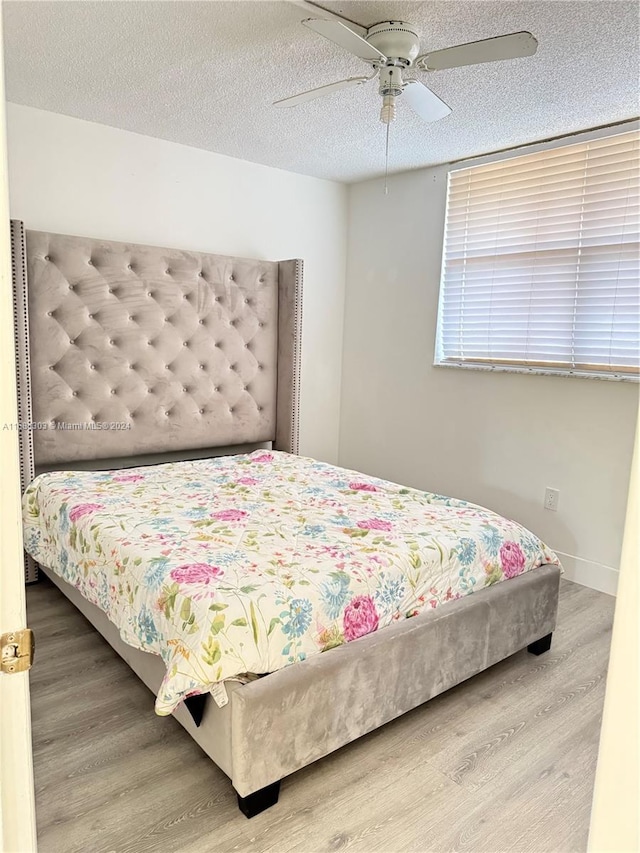 bedroom featuring ceiling fan, hardwood / wood-style floors, and a textured ceiling