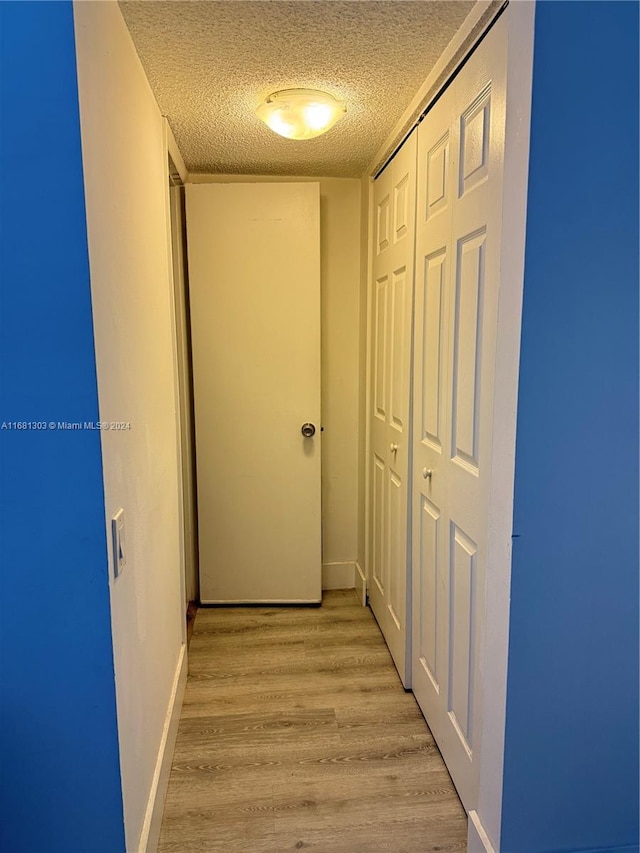 hall featuring light hardwood / wood-style flooring and a textured ceiling