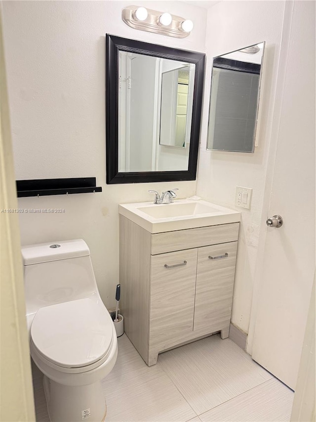 bathroom featuring tile patterned flooring, vanity, and toilet