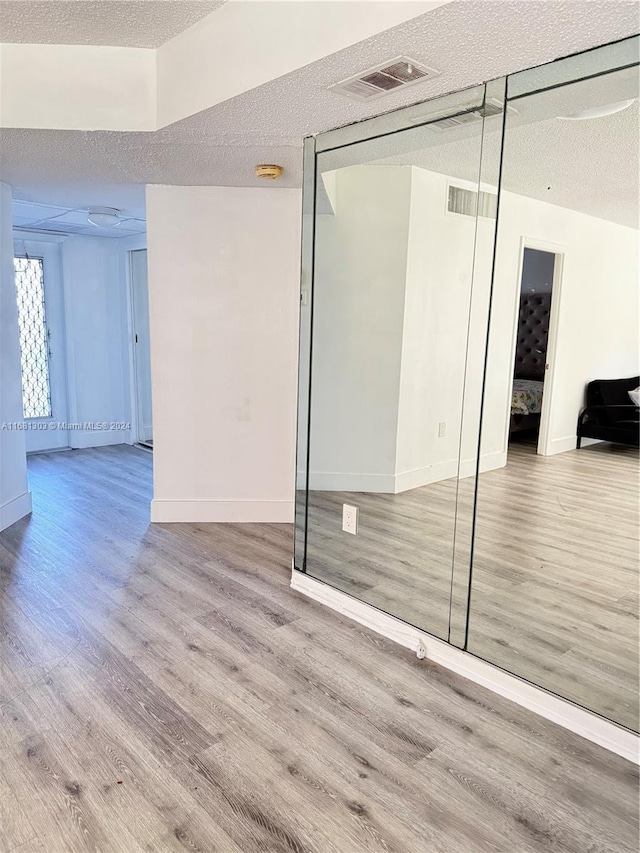 empty room with light hardwood / wood-style flooring and a textured ceiling