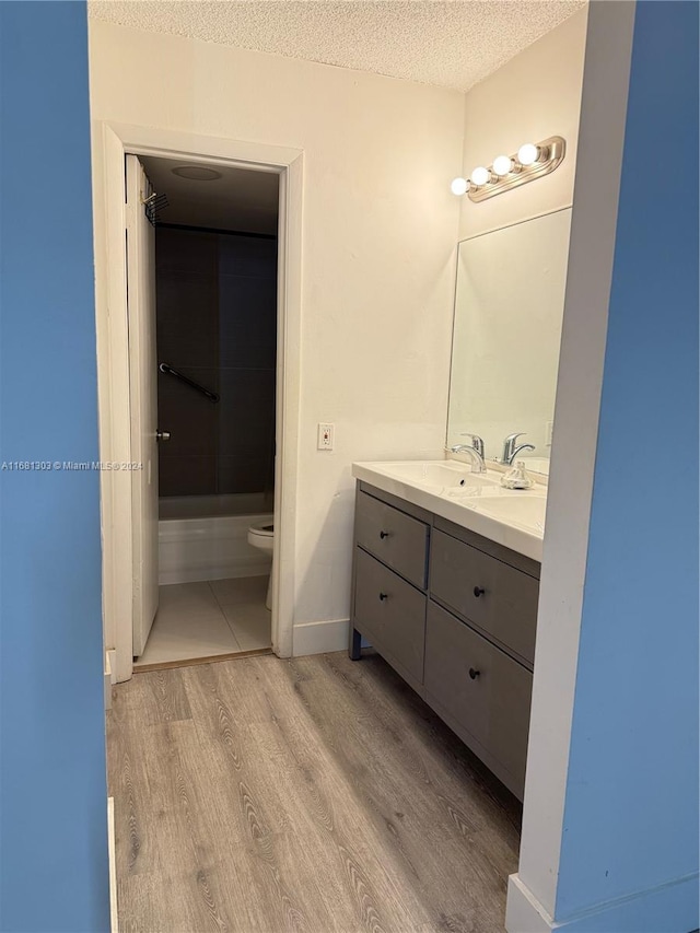 bathroom featuring hardwood / wood-style floors, vanity, toilet, and a textured ceiling