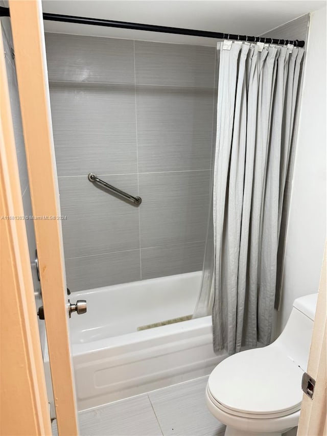 bathroom with tile patterned floors, shower / tub combo, and toilet