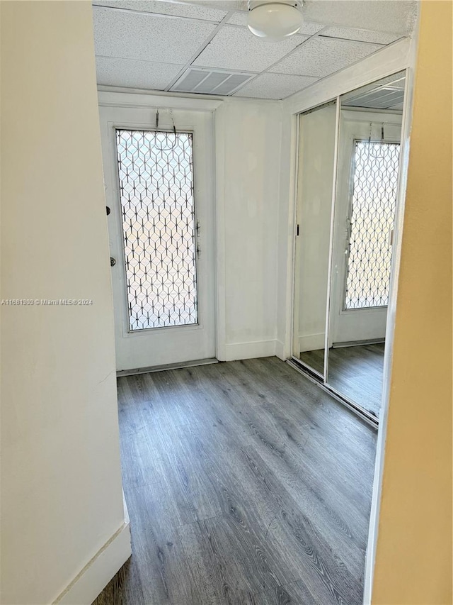 empty room with a paneled ceiling, wood-type flooring, and a wealth of natural light