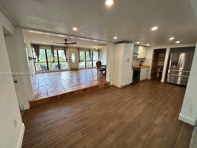 unfurnished living room featuring ceiling fan and dark hardwood / wood-style flooring