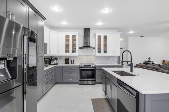 kitchen with white cabinetry, sink, stainless steel appliances, wall chimney range hood, and tasteful backsplash