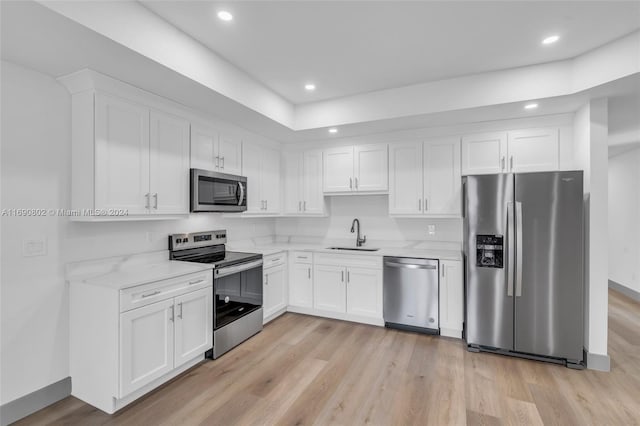 kitchen featuring white cabinetry, appliances with stainless steel finishes, light stone counters, and light hardwood / wood-style flooring