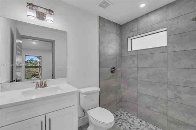 bathroom with toilet, vanity, and a tile shower