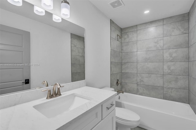 full bathroom featuring vanity, tiled shower / bath combo, and toilet