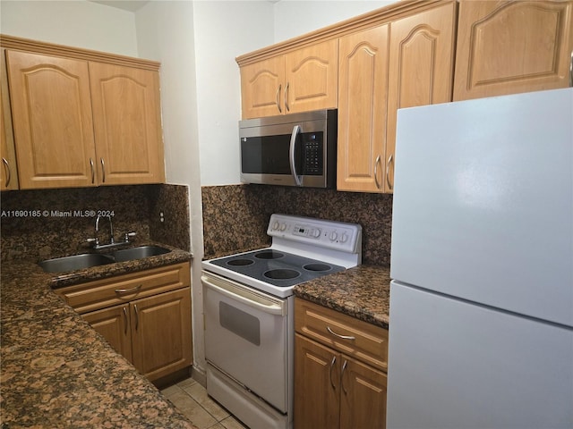 kitchen with tasteful backsplash, dark stone counters, white appliances, sink, and light tile patterned floors