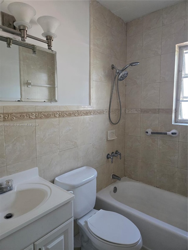 full bathroom with tiled shower / bath, vanity, toilet, and tile walls