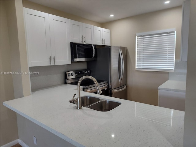 kitchen featuring light stone countertops, stainless steel appliances, white cabinetry, and sink