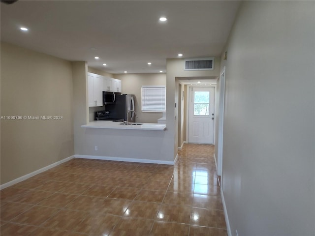 kitchen with white cabinets, kitchen peninsula, stainless steel appliances, and light tile patterned floors