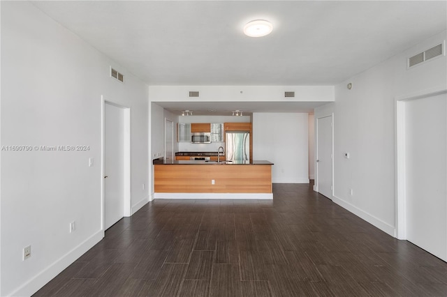 unfurnished living room featuring sink and dark hardwood / wood-style flooring