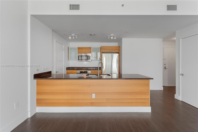 kitchen with kitchen peninsula, appliances with stainless steel finishes, sink, and dark hardwood / wood-style floors