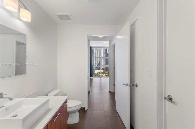 bathroom with hardwood / wood-style flooring, vanity, and toilet