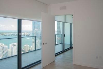 unfurnished room with floor to ceiling windows and hardwood / wood-style floors