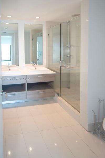 bathroom with tile patterned flooring, an enclosed shower, and vanity