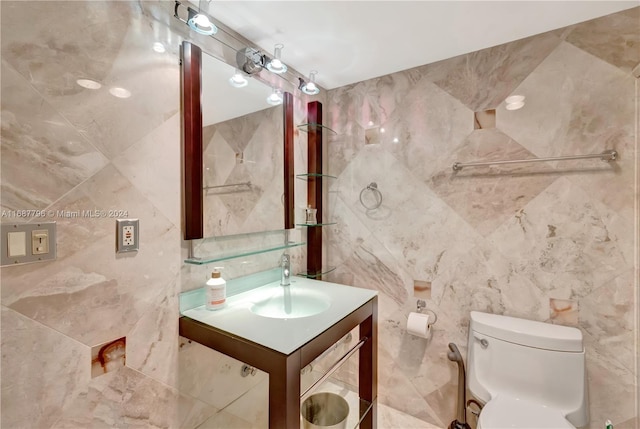 bathroom with vanity, tile walls, and toilet