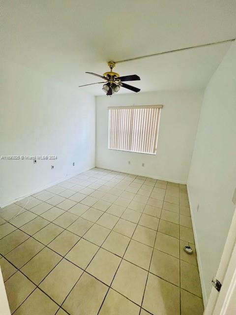 empty room with ceiling fan and light tile patterned floors