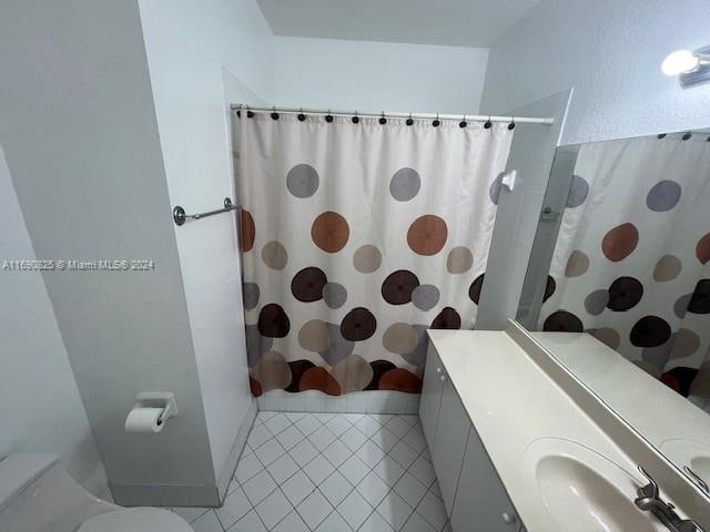 bathroom featuring a shower with curtain, tile patterned floors, toilet, and vanity