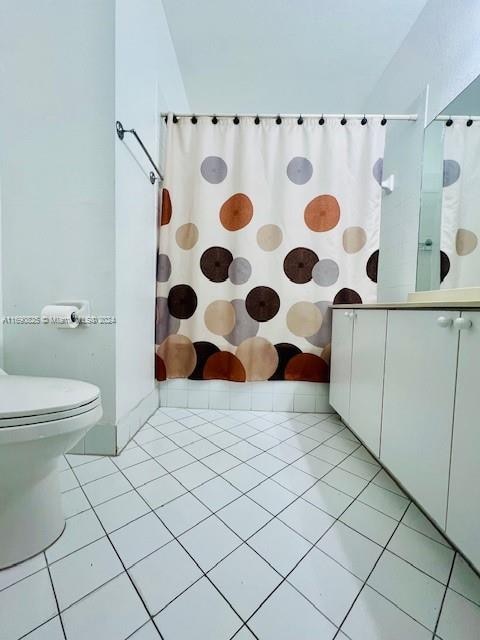 bathroom featuring tile patterned flooring, a shower with shower curtain, and toilet