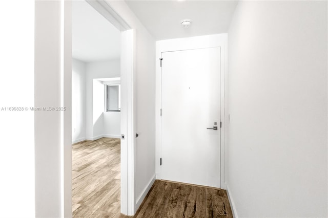 corridor featuring wood finished floors and baseboards
