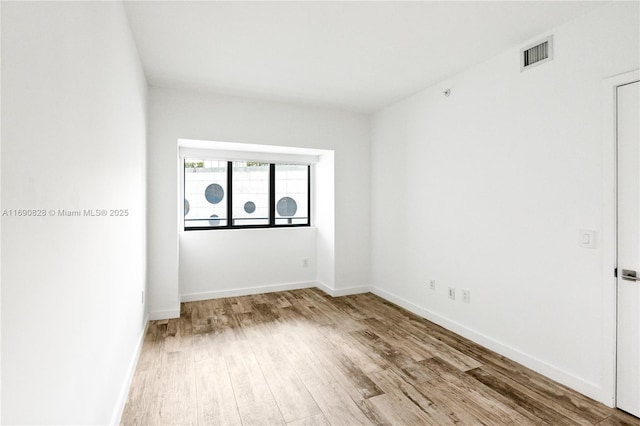 unfurnished room featuring baseboards, wood finished floors, and visible vents