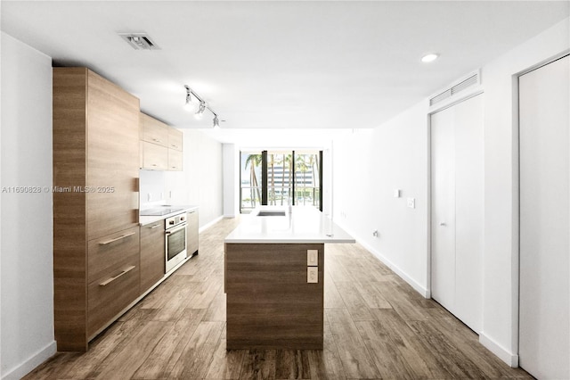 kitchen featuring wood finished floors, modern cabinets, oven, and visible vents