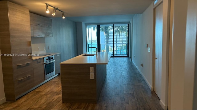 kitchen featuring wood-type flooring, sink, stainless steel oven, a center island with sink, and black electric cooktop