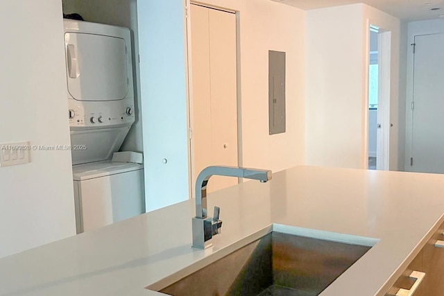 laundry room with stacked washer / dryer, a sink, and electric panel