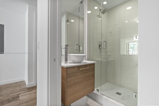 bathroom with recessed lighting, wood finished floors, vanity, and a stall shower
