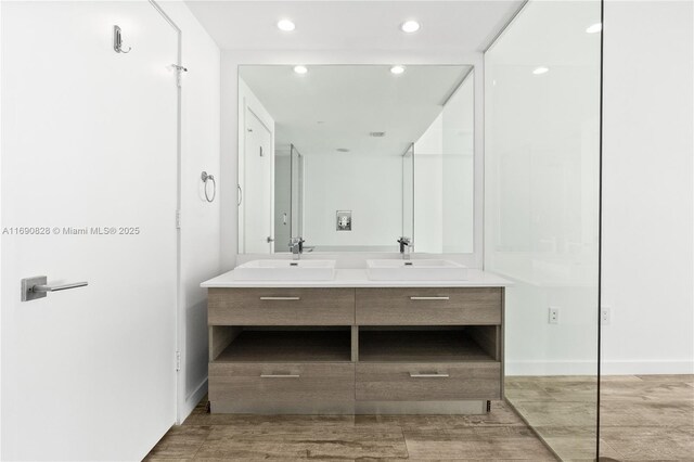 full bath with wood finished floors, a sink, recessed lighting, and double vanity