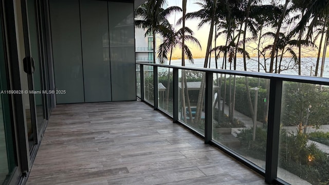 balcony at dusk featuring a water view