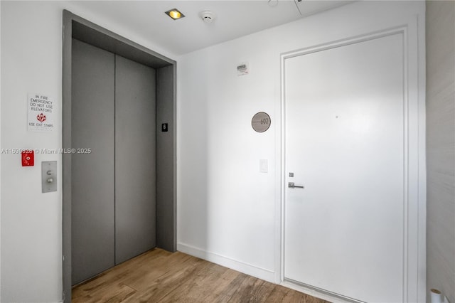 corridor featuring elevator and wood finished floors