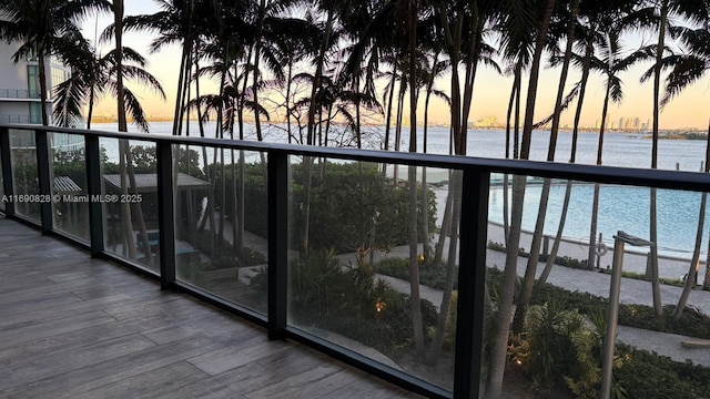 balcony at dusk featuring a water view