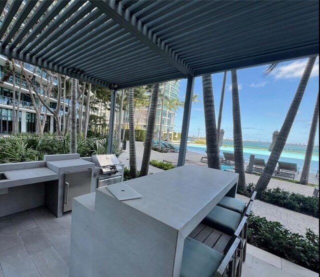 view of patio / terrace featuring a grill, a water view, exterior kitchen, and outdoor wet bar