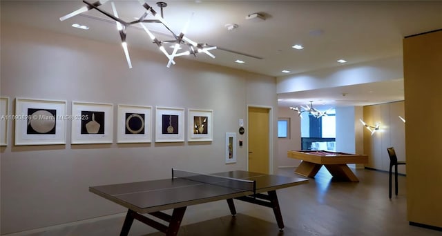 game room with a towering ceiling, a notable chandelier, and billiards