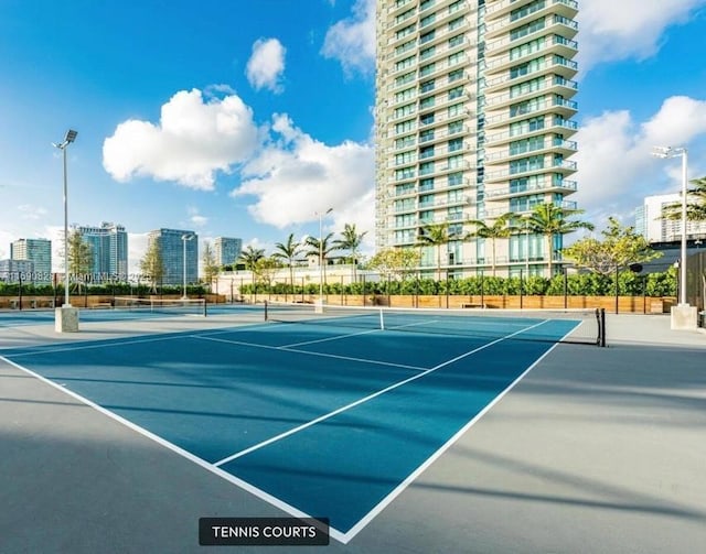 view of tennis court featuring community basketball court and fence
