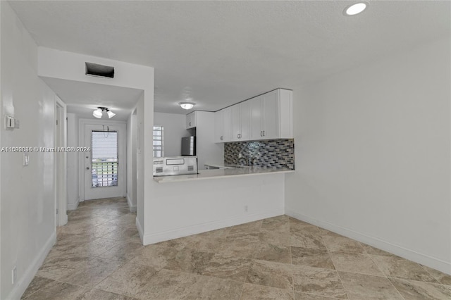 kitchen with sink, white cabinetry, kitchen peninsula, and decorative backsplash