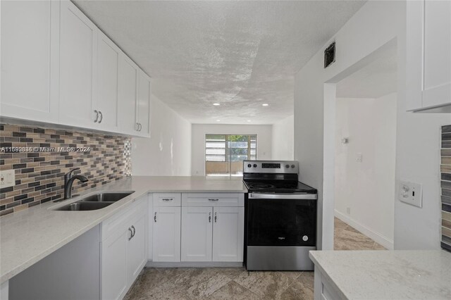 110 Lake Meryl Dr Unit 213, West Palm Beach, FL 33411 - kitchen with stainless steel range with electric cooktop, a sink, decorative backsplash, white cabinets, and a peninsula