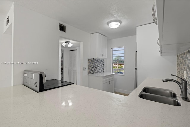 110 Lake Meryl Dr Unit 213, West Palm Beach, FL 33411 - kitchen with a sink, decorative backsplash, white cabinetry, and a textured ceiling