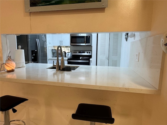 kitchen with stainless steel appliances, a kitchen bar, and sink