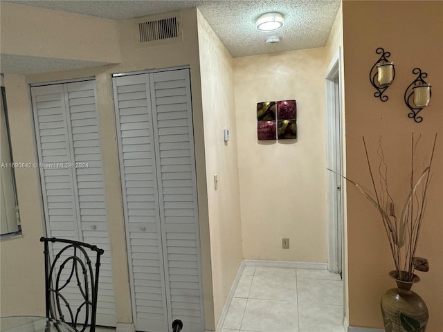 hallway featuring a textured ceiling and light tile patterned floors