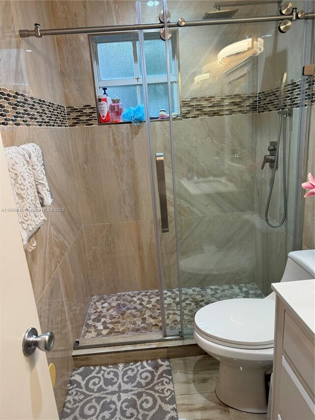 bathroom featuring vanity, toilet, and a shower with door