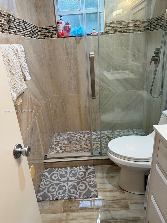 bathroom with walk in shower, vanity, and toilet