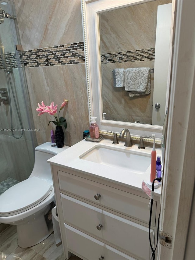 bathroom featuring toilet, vanity, and a shower with shower door